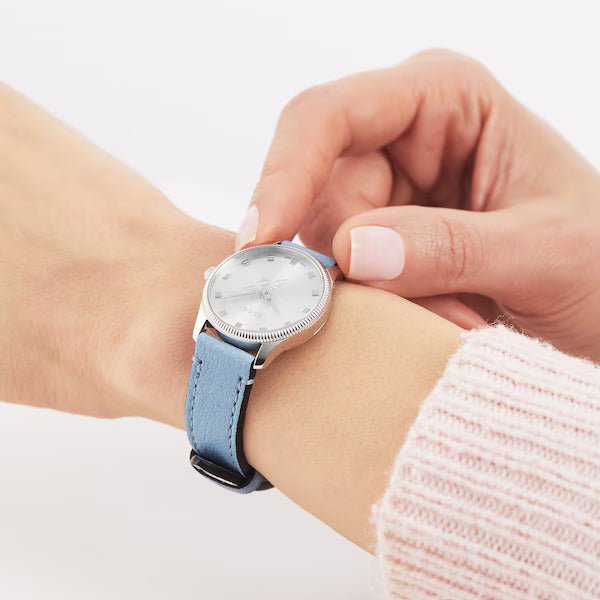 Gucci G-Timeless watch worn on wrist with silver dial and blue leather strap