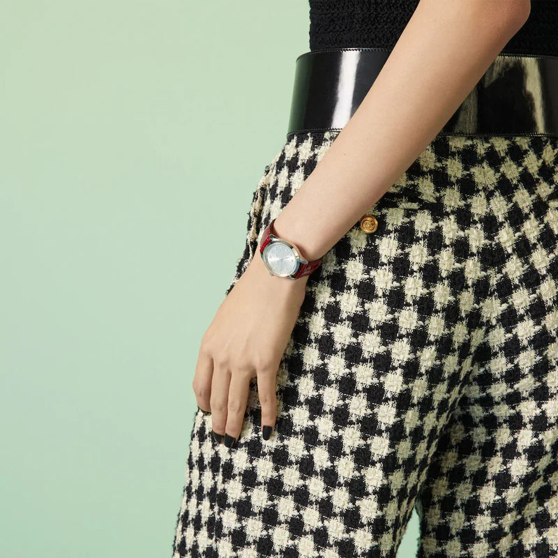 Gucci G-Timeless watch worn on wrist showing silver dial with bee pattern and red leather strap