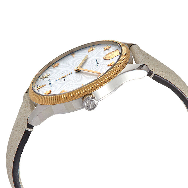 Gucci G-Timeless watch angled side view showing gold bezel and cream leather strap