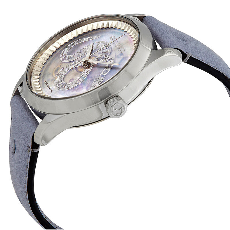 Gucci G-Timeless automatic watch on wrist with stainless steel case and blue leather strap