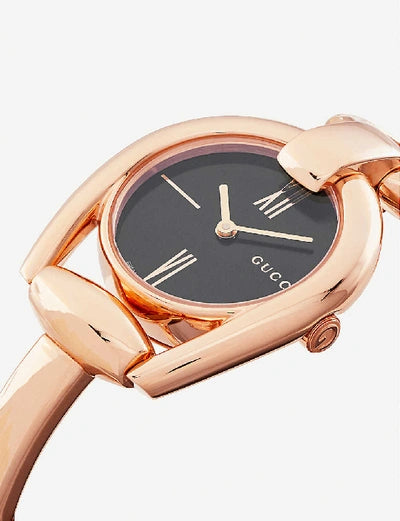 Close-up of Gucci Horsebit watch dial with black face, rose gold case, and Roman numeral hour markers