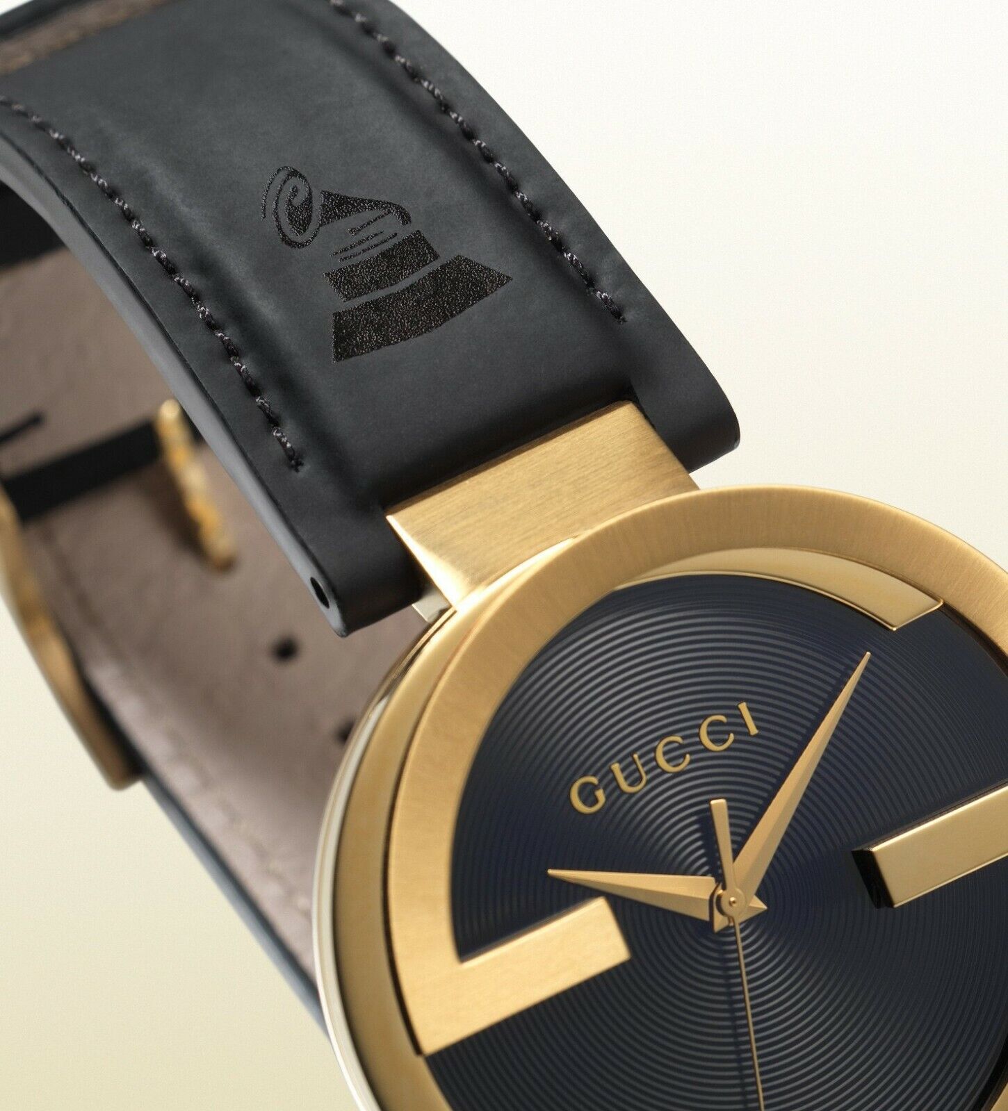 Gucci Interlocking Grammy watch showing gold case and black leather strap detail