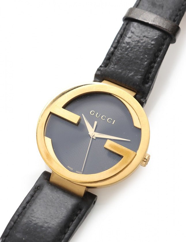 Gucci Interlocking Grammy watch worn on wrist with black leather strap