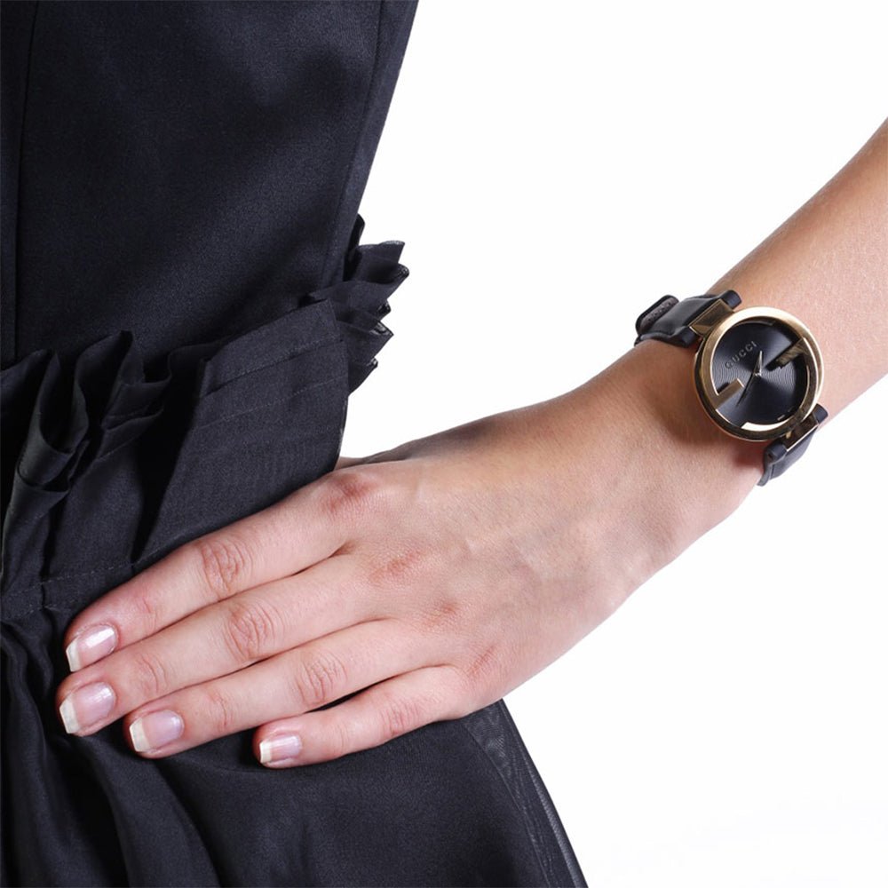 Gucci Interlocking watch worn on wrist with black leather strap and gold-tone case