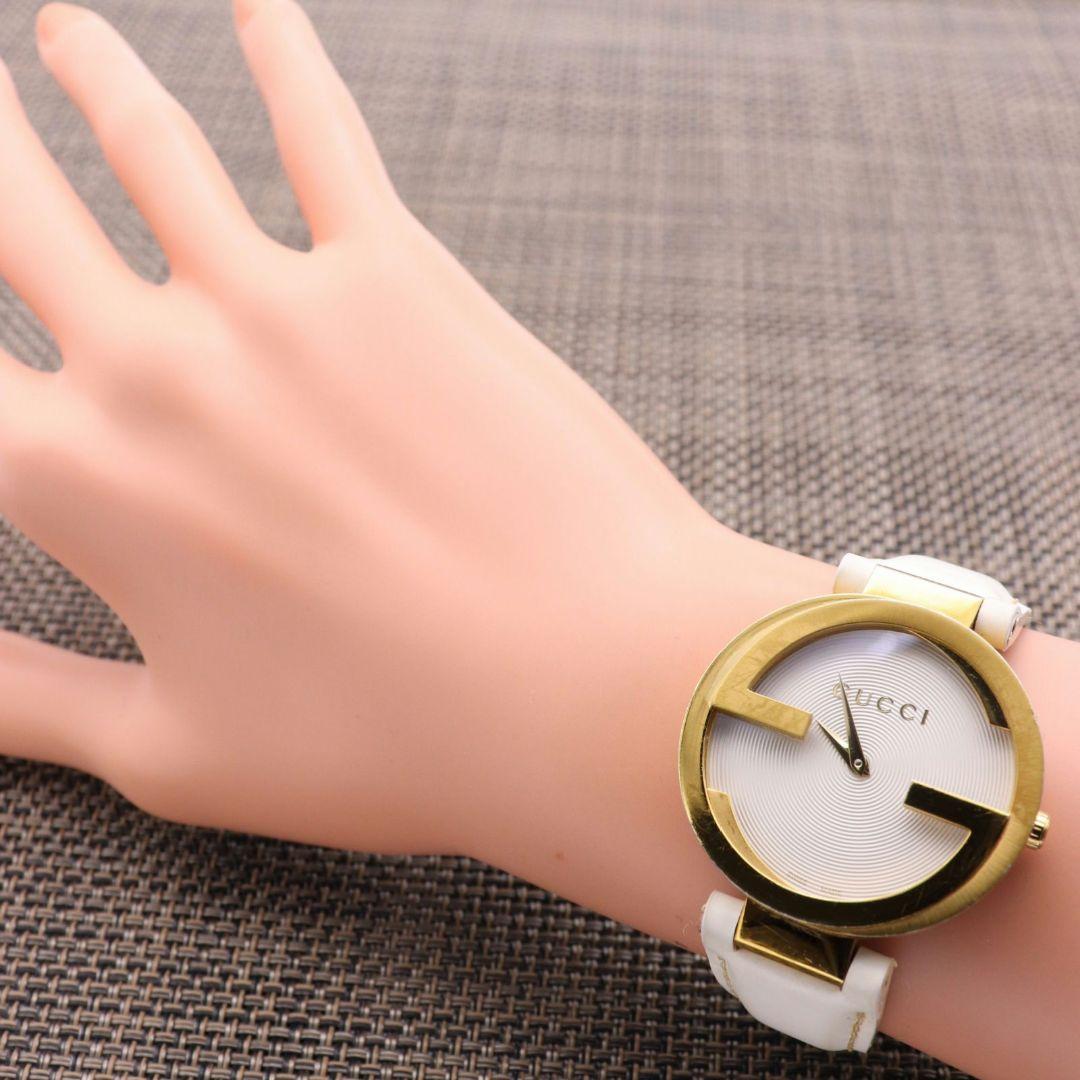 Gucci Interlocking watch styled on wrist with white strap and gold-tone case