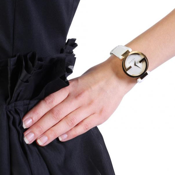 Gucci Interlocking watch on wrist worn with white leather strap and gold case