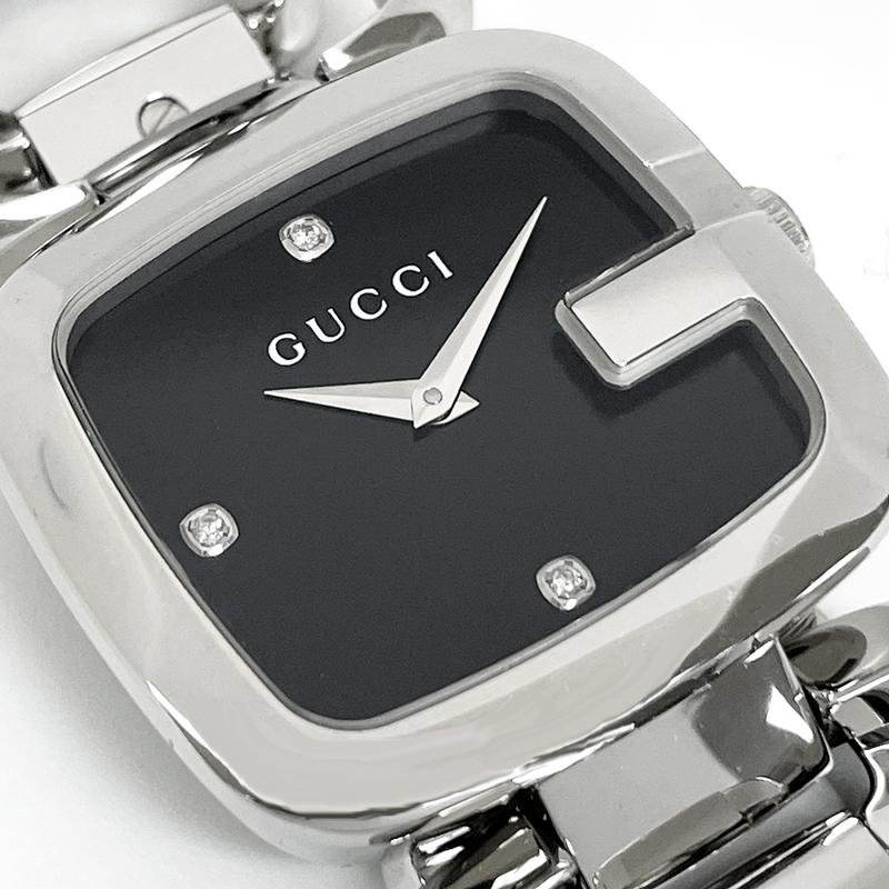 Black dial detail with GUCCI branding, white hands, and diamond hour markers