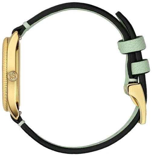 Gucci G-Timeless watch worn on wrist showing yellow gold case and green leather strap
