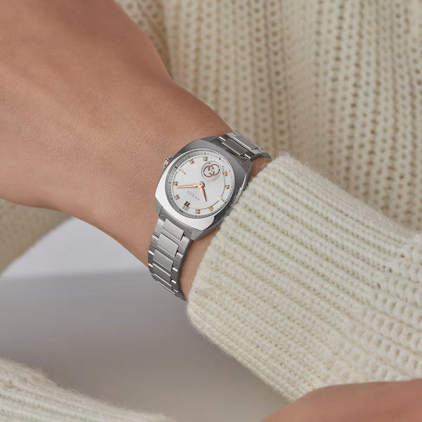 Gucci YA142510 stainless steel watch worn on wrist with cream-colored sweater