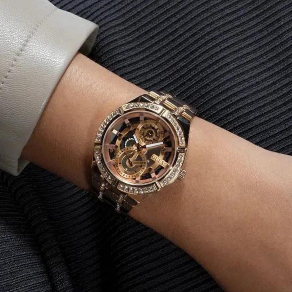 Guess Allara rose gold watch on wrist showing skeleton dial and crystal bezel