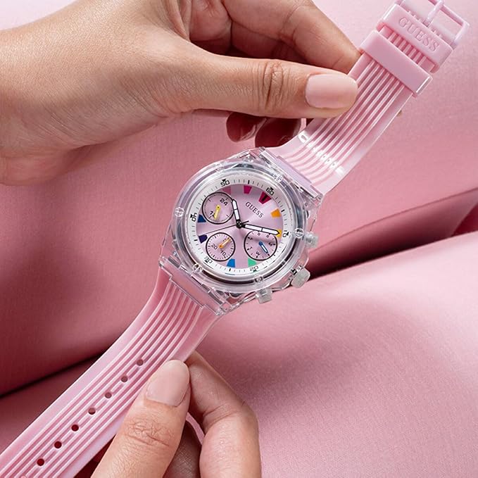 Hands adjusting Guess Athena watch strap, displaying pink dial and case details