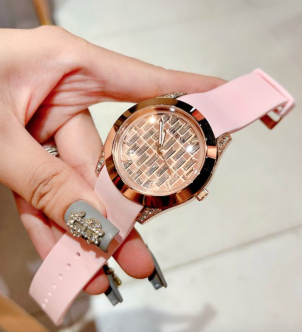Guess Clarity women's watch worn on wrist showing rose gold case with black accents and pink strap