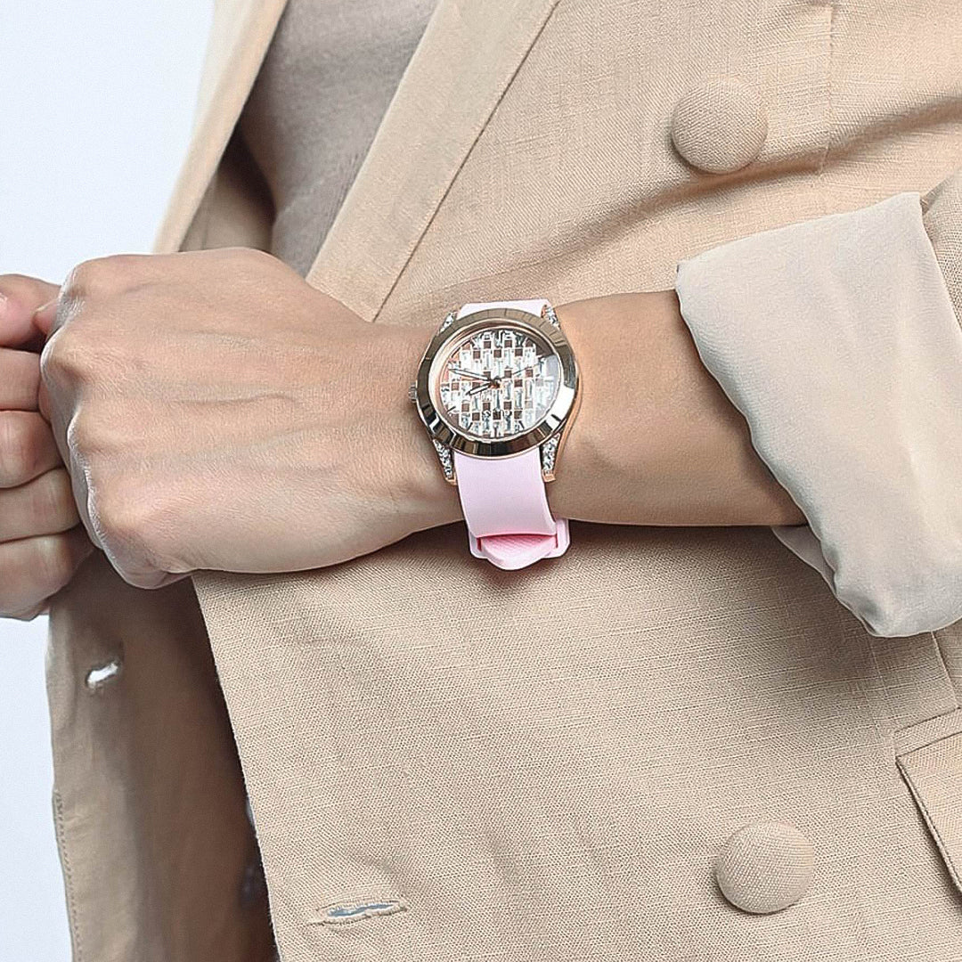 Guess Clarity watch on wrist with beige blazer, displaying rose gold case and pink silicone band