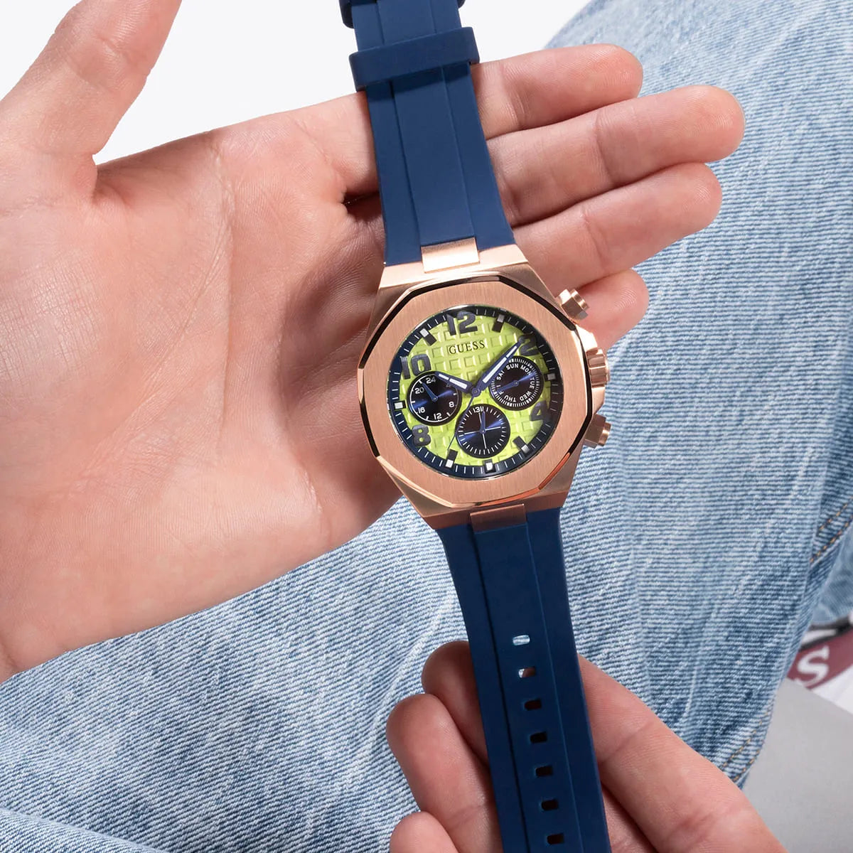 GUESS Empire chronograph watch held in hand showing full view of case, dial, and blue strap