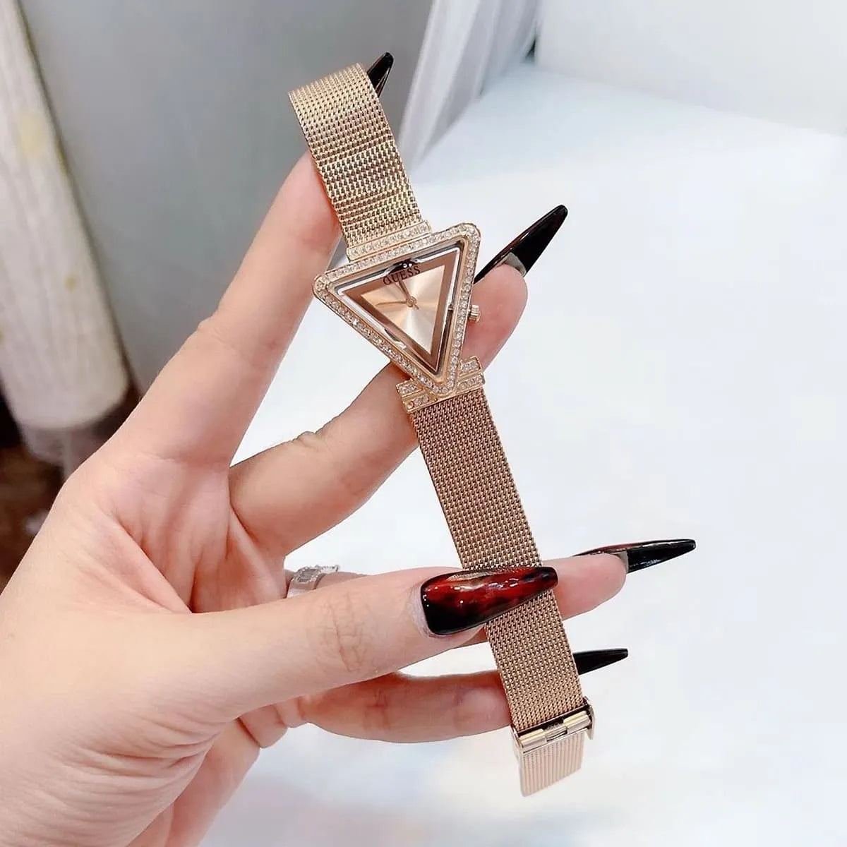Guess Fame rose gold women watch on wrist showing triangular face with crystal details