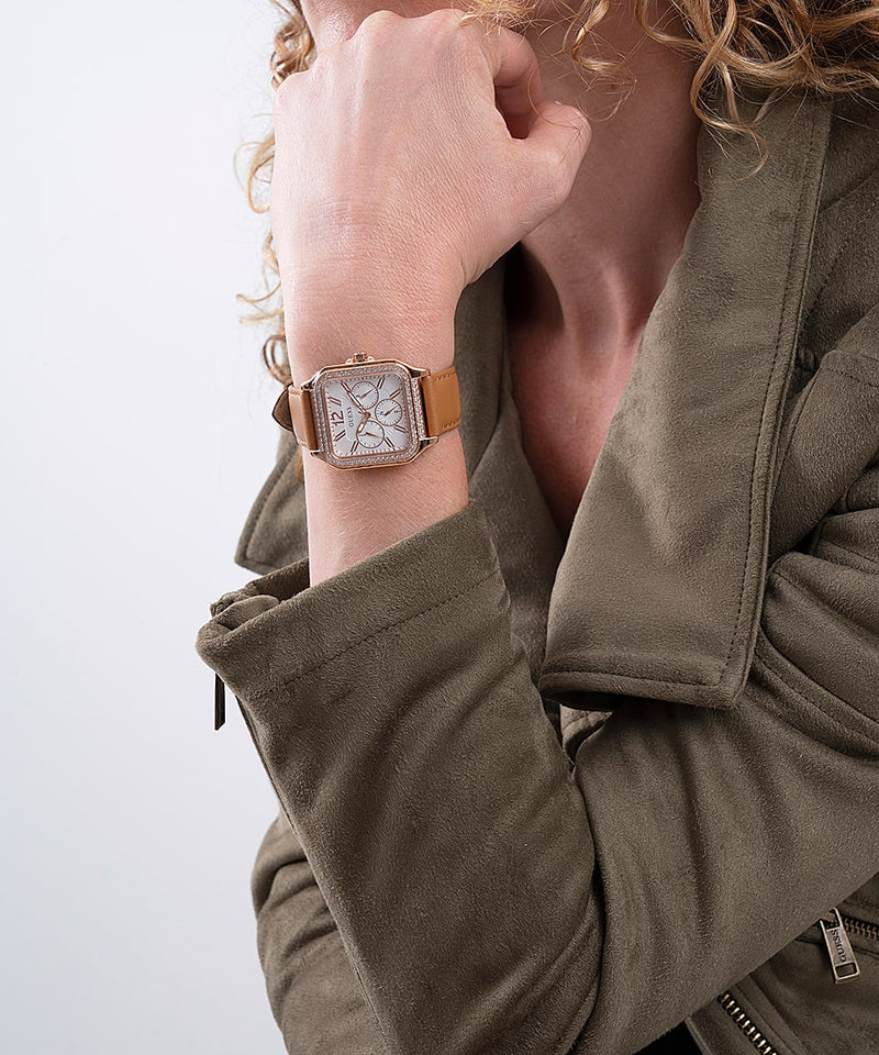Guess watch worn on wrist showing silver dial and brown leather strap