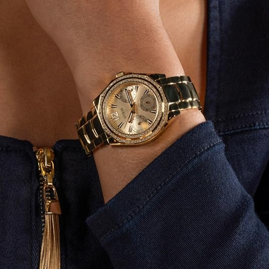 Gold-tone GUESS multifunction watch worn on wrist with crystal bezel