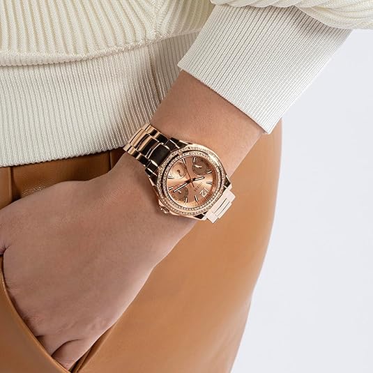 Rose gold Guess watch worn on wrist with cream sweater