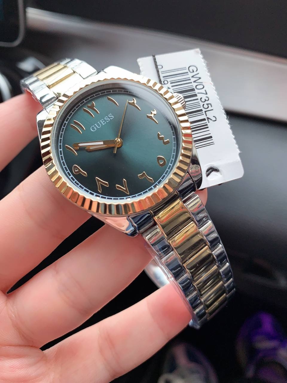 GUESS GW0735L2 worn on wrist with green dial and two-tone bracelet, shown with authenticity tag