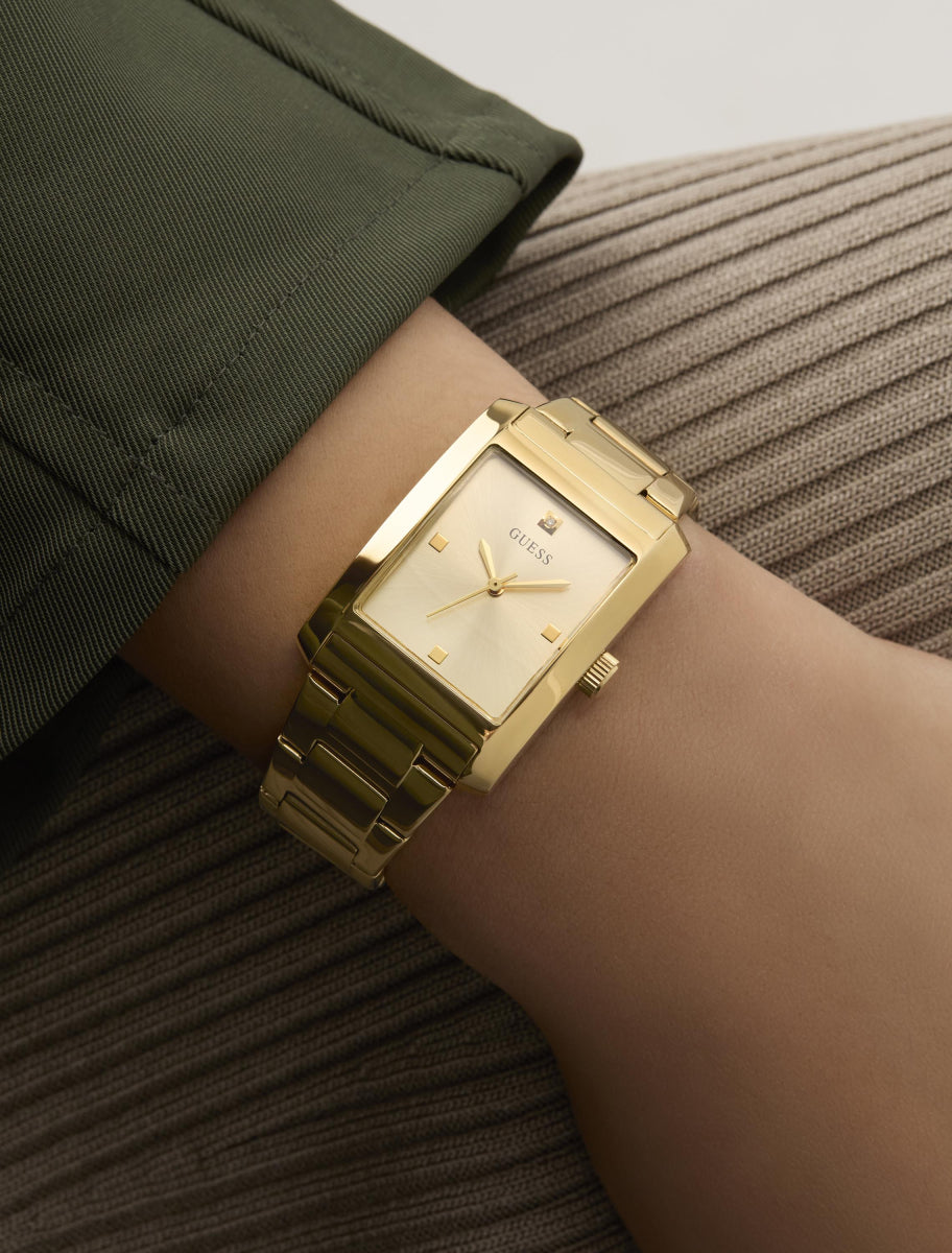 Guess gold watch worn on wrist with champagne rectangular dial