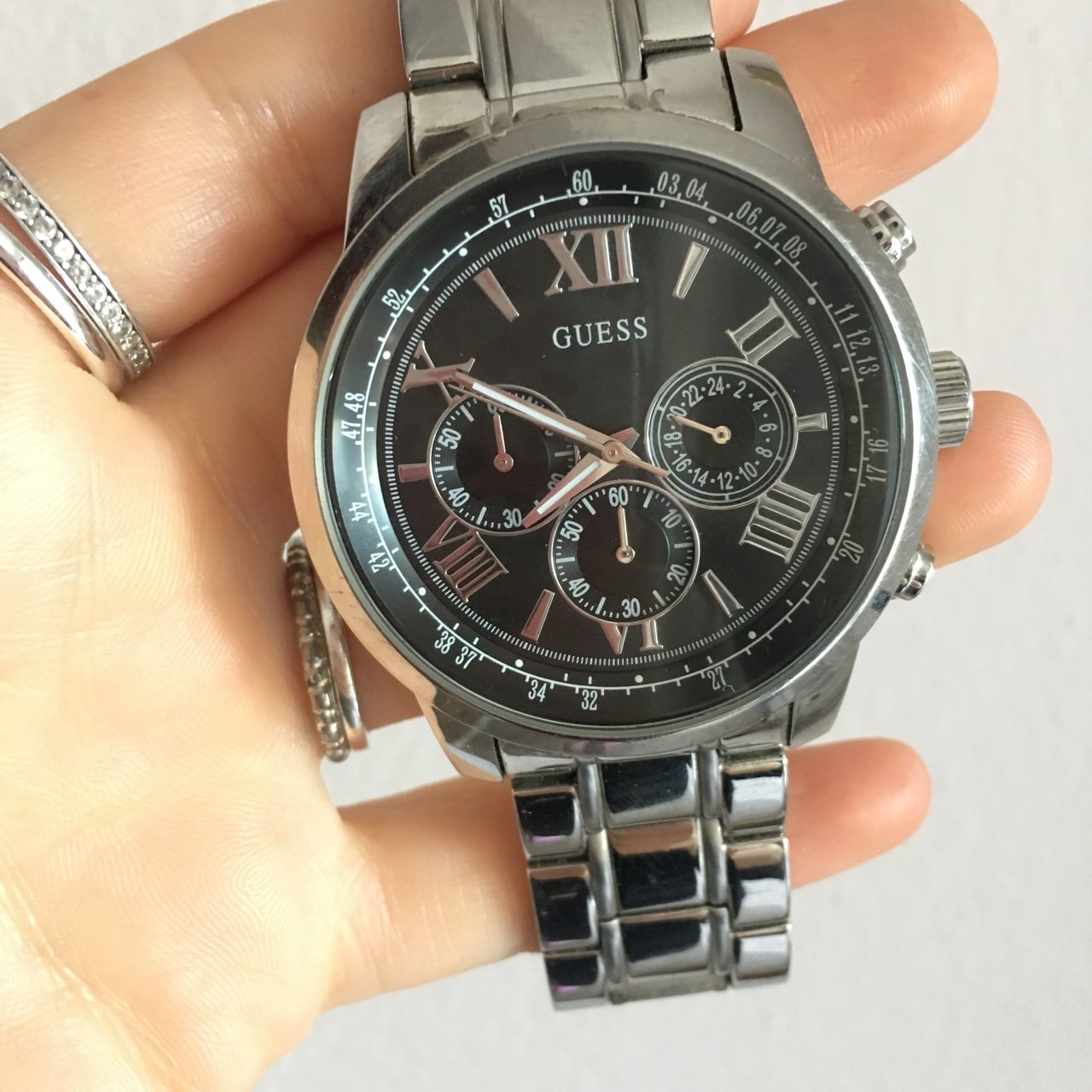 Guess Horizon chronograph watch held in hand showing black dial with Roman numerals