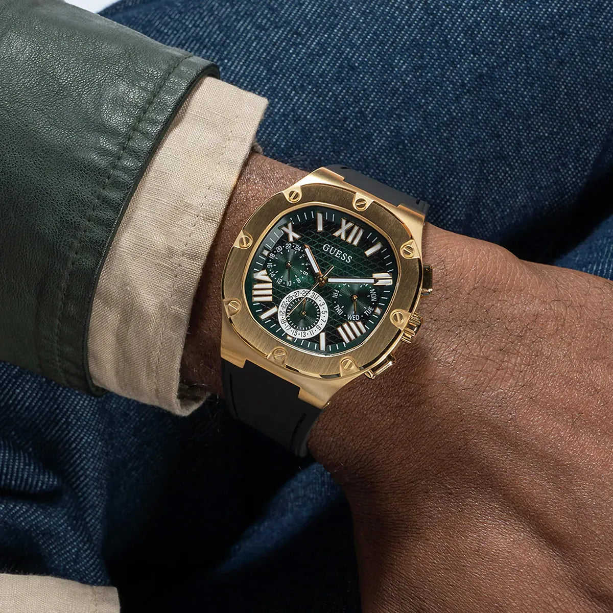 Guess Legacy gold-tone chronograph watch worn on wrist with layered outfit