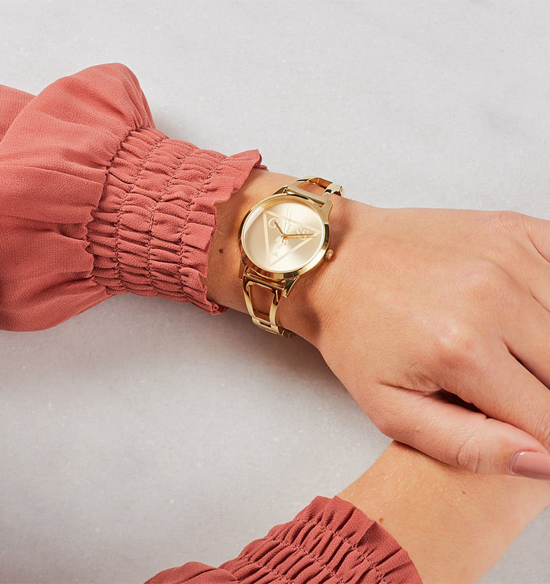 Guess Lola rose gold watch worn on wrist with coral ruffled sleeve