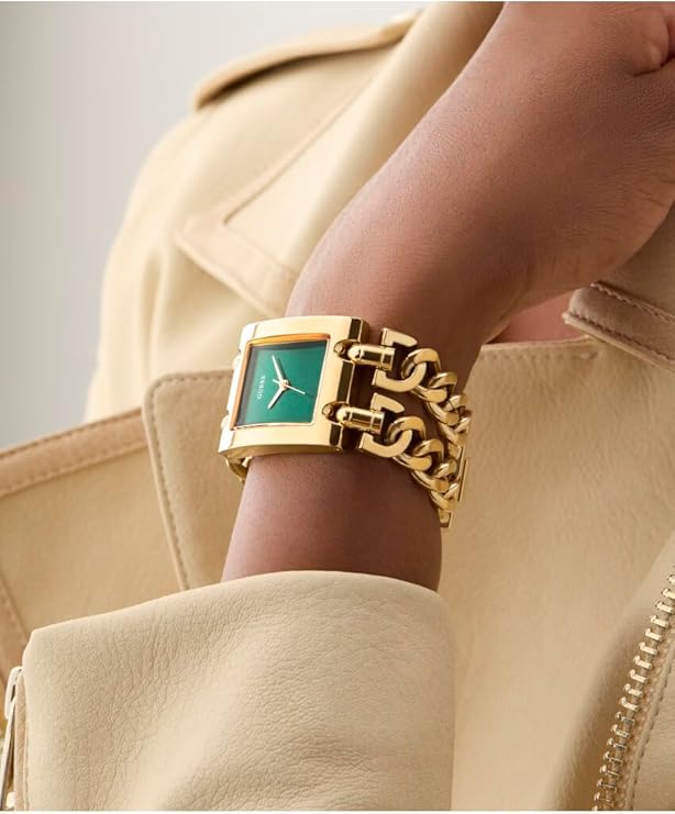 GUESS MOD HEAVY METAL ladies watch worn on wrist featuring gold bracelet and green rectangular dial
