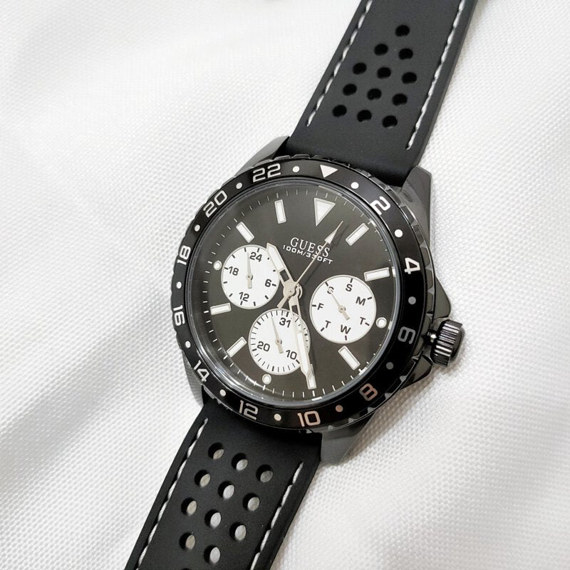 Guess Odyssey chronograph watch worn on wrist with black perforated rubber strap