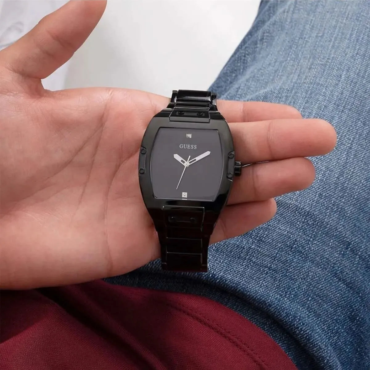 Guess Phoenix black watch held in hand showing square dial and compact size