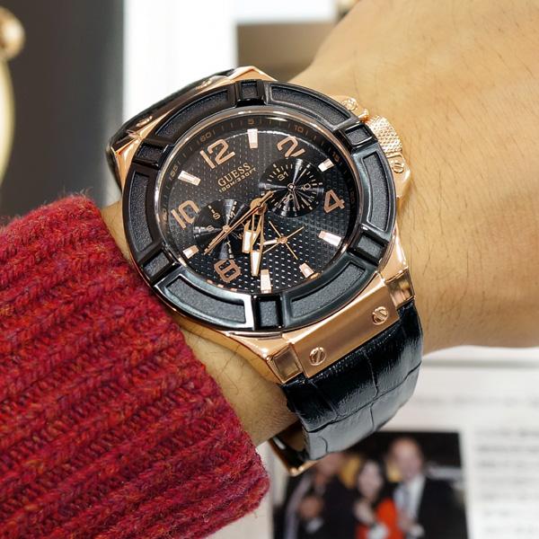 Guess Rigor men's watch on wrist displaying black leather strap and rose gold case