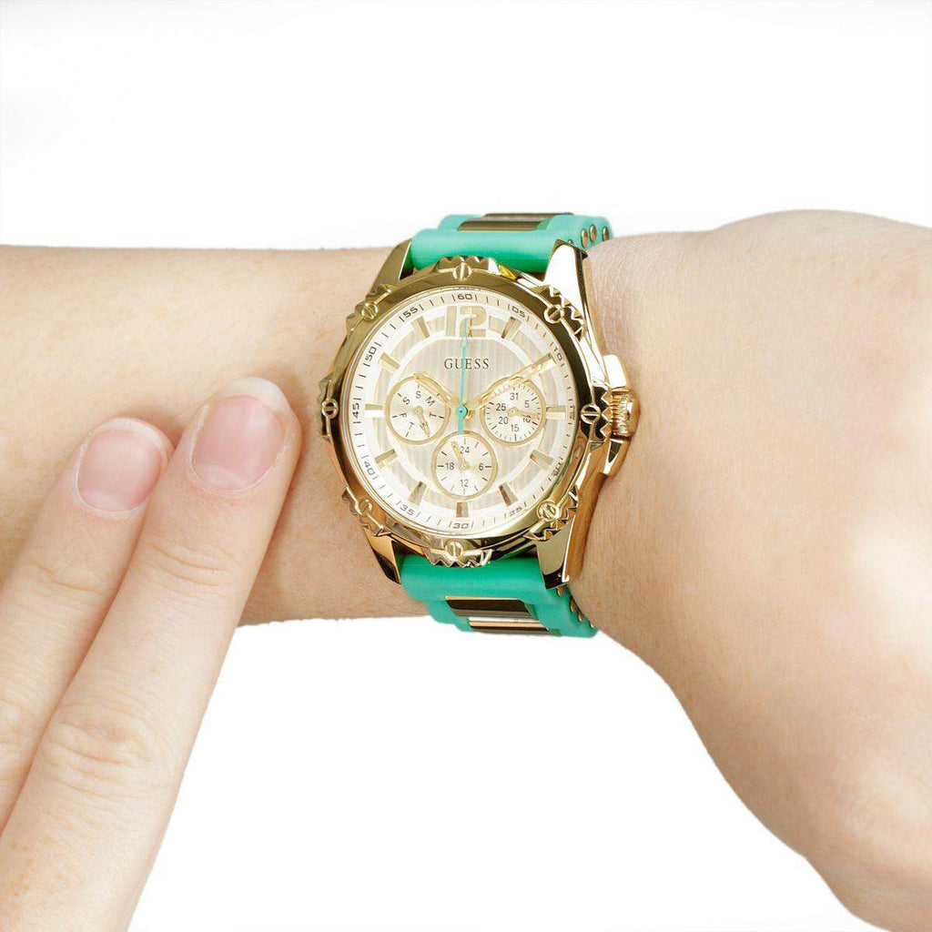 Guess watch with turquoise silicone strap and gold-tone case worn on wrist