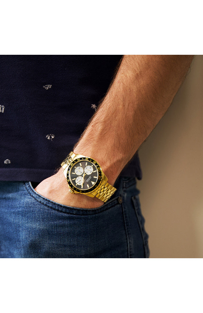 Guess W1107G4 watch worn on wrist showing black dial and gold bracelet in everyday setting