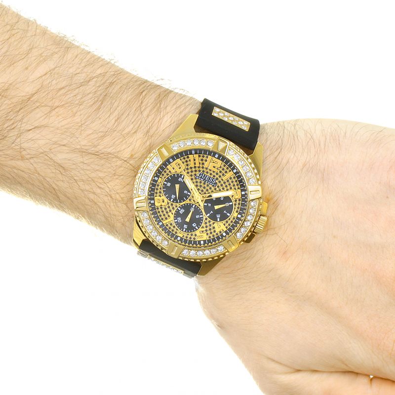 Guess gold chronograph watch on wrist with black silicone band