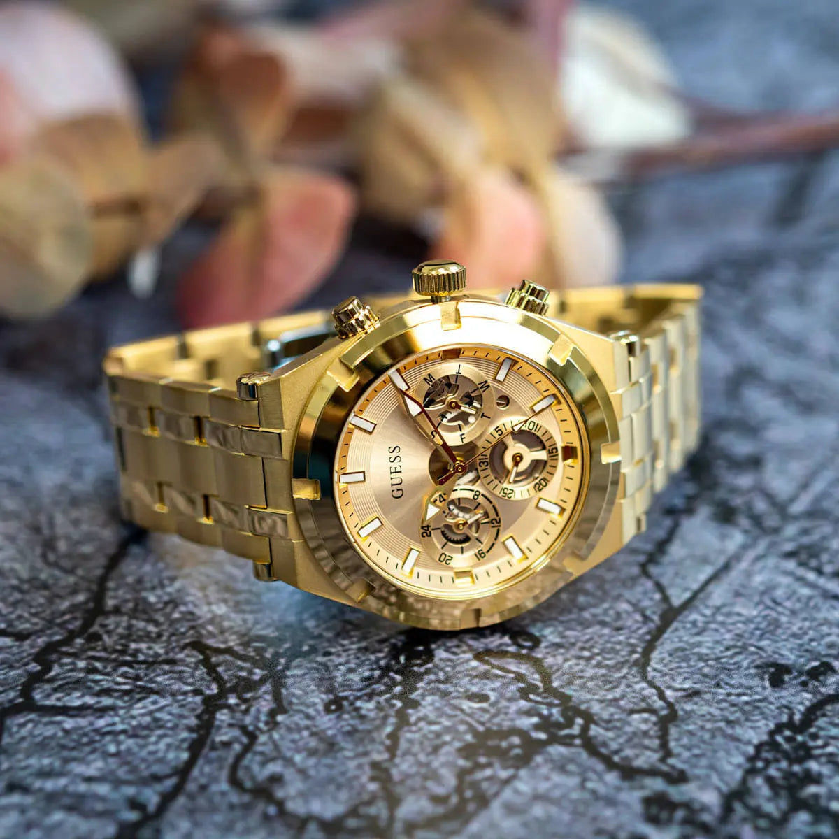 Guess Continental watch displayed on weathered surface showing golden case and chronograph dial detail