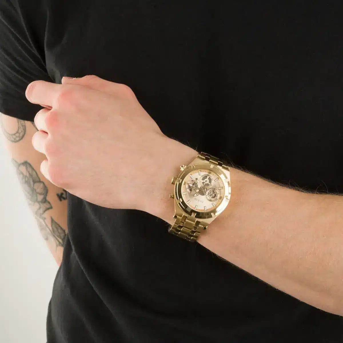 Guess Continental gold watch worn on wrist displaying champagne dial with chronograph subdials