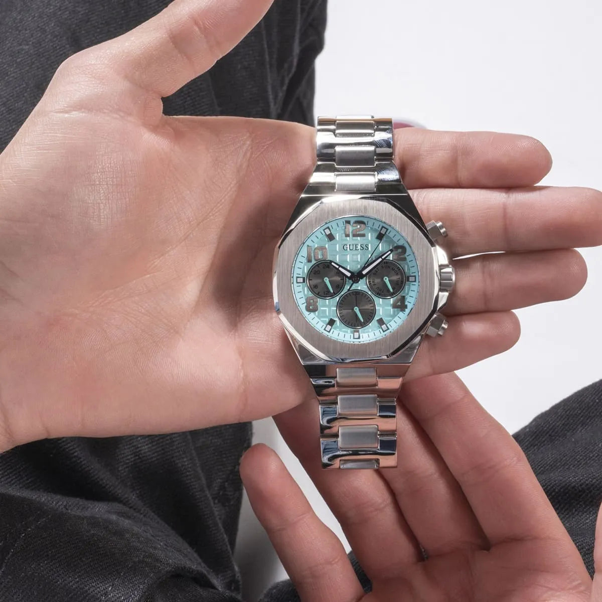 Guess GW0489G3 silver watch held in hand showing turquoise dial and stainless steel band