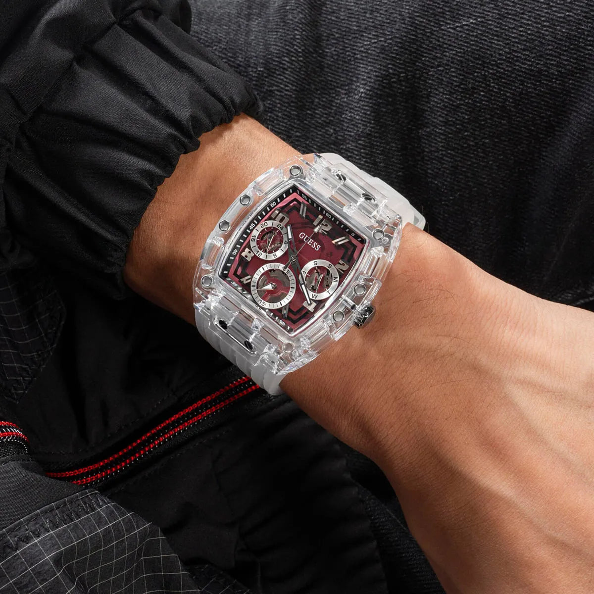 Guess Phoenix watch on wrist in dark clothing showing transparent case