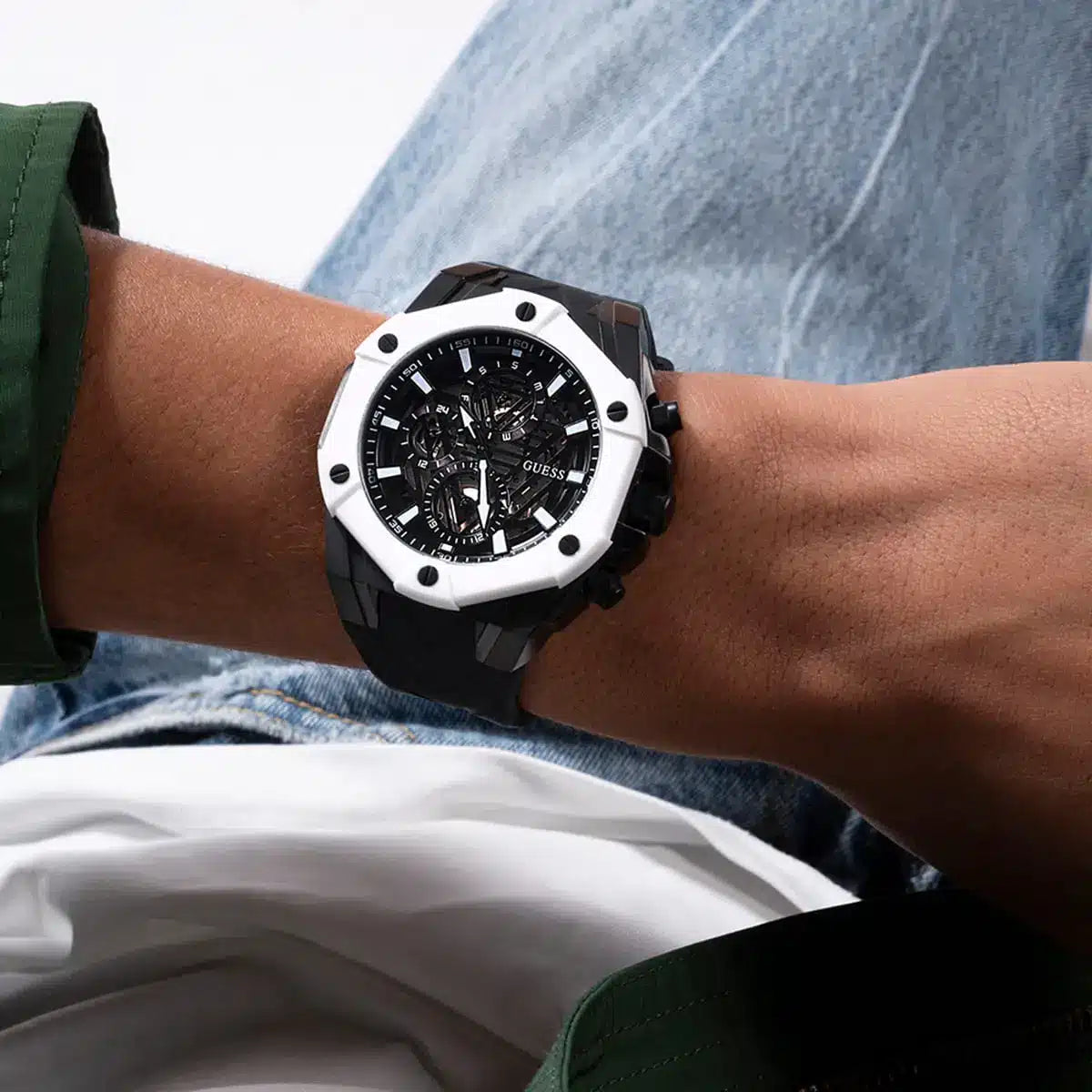 Guess GW0579G1 watch on wrist showing skeleton dial face and black silicone strap