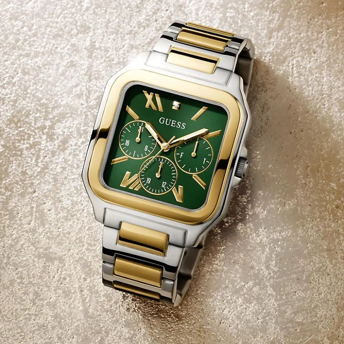 GUESS GW0631G1 square watch on textured surface showing multi-tone metal case and green dial