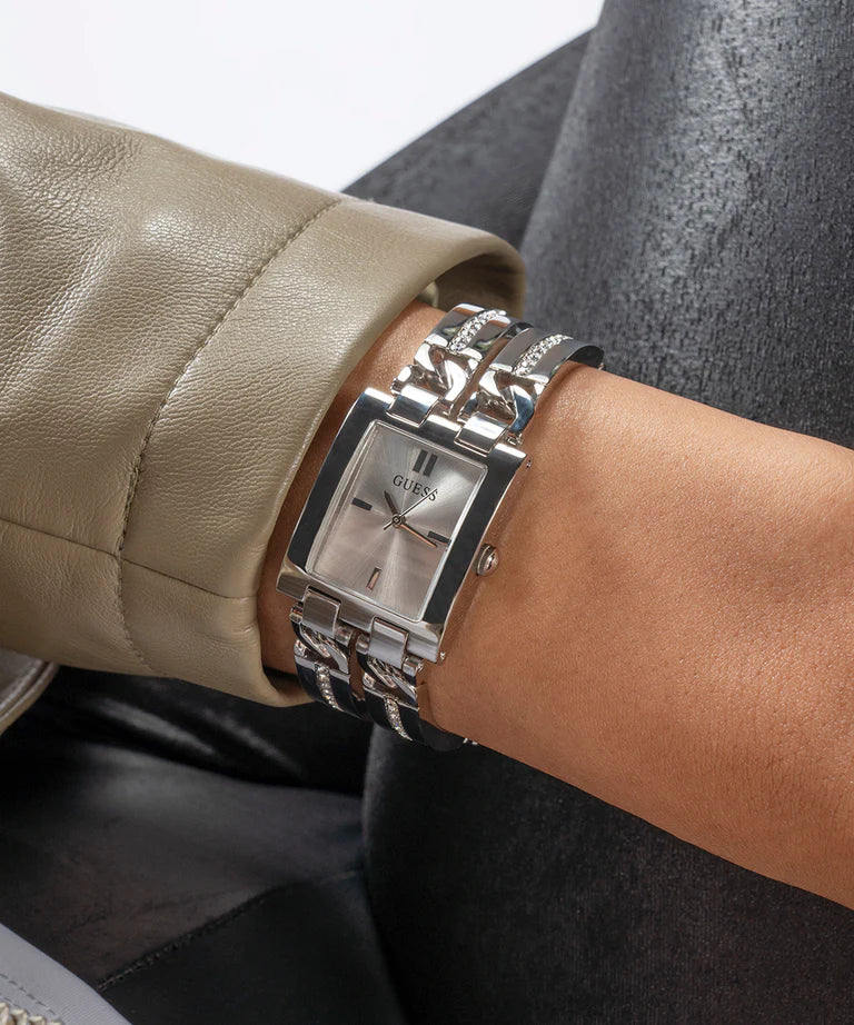 GUESS silver square watch worn on wrist with taupe jacket and dark sweater