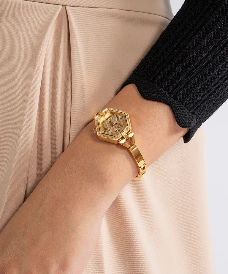 Gold tone GUESS hexagonal watch worn on wrist with matching gold bracelet