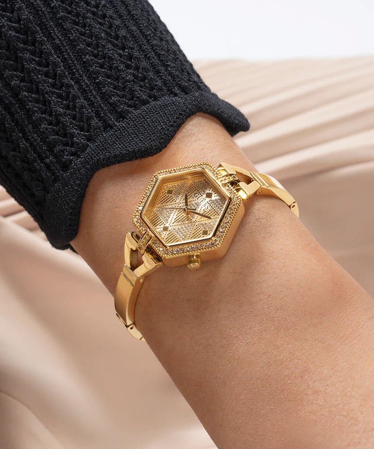 GUESS gold analog watch on wrist showing champagne dial and hexagonal case