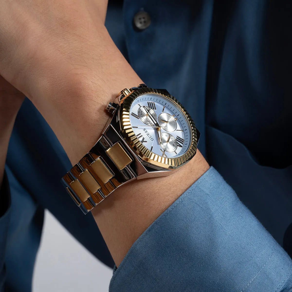GUESS Equity chronograph watch on wrist showing blue and white dial with gold bezel