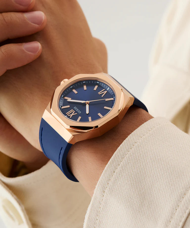 GUESS rose gold watch worn on wrist with blue silicone strap