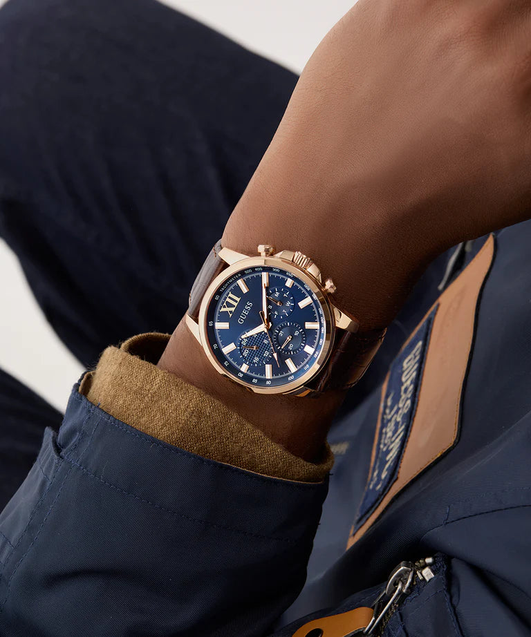 GUESS GW0901G3 chronograph watch on wrist displaying rose gold case and navy dial with Roman numerals