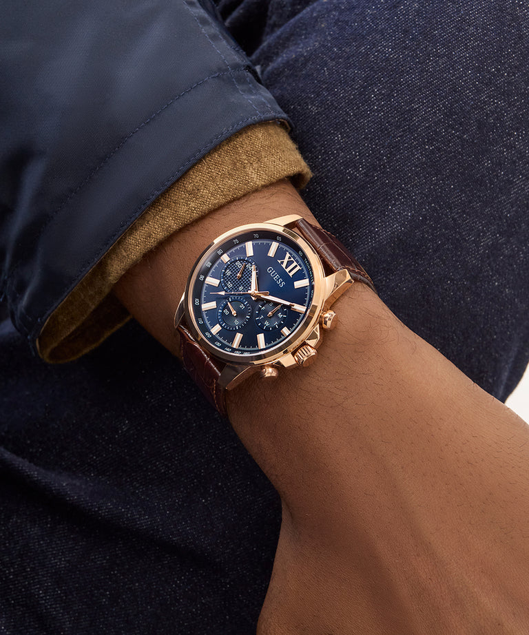 GUESS GW0901G3 watch worn on wrist showing rose gold case with brown leather strap and navy blue dial