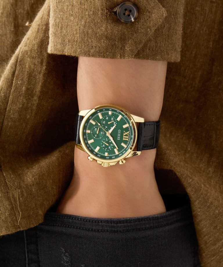 GUESS GW0901G4 on-wrist shot showing green dial and gold case worn with earth-tone sweater