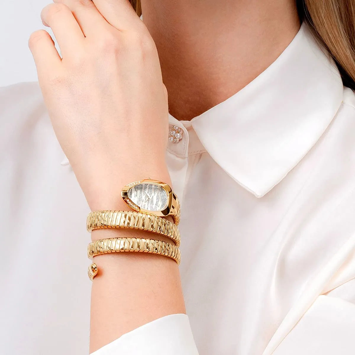 Just Cavalli Serpente gold watch worn on wrist with silver glitter dial and crystal accents