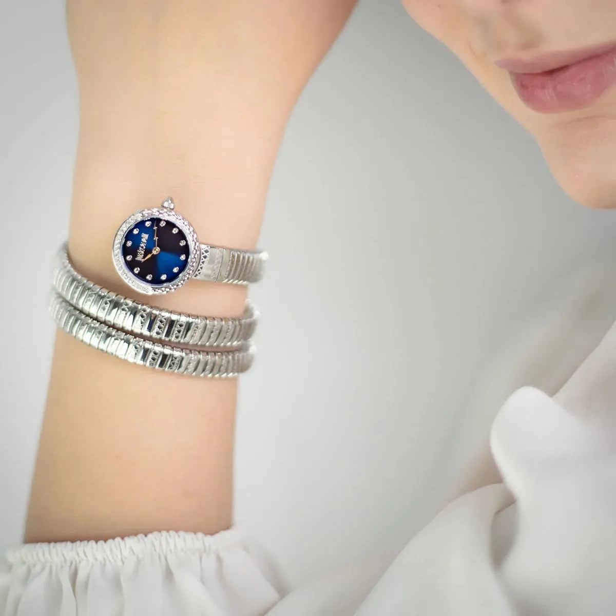 Just Cavalli Signature Snake watch worn on wrist showing blue dial and triple-coil snake strap